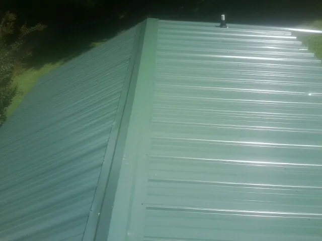 New green metal panels meeting at the ridge of a roof — Flat Roof Repair work by our crew in Sturgeon Bay