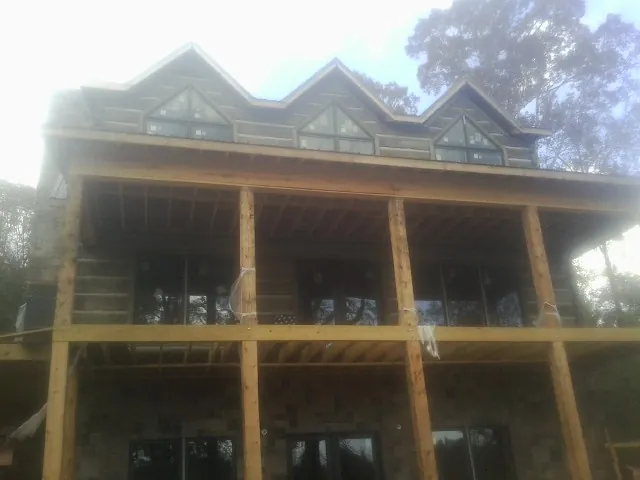 Dormers and porch framing on a large log home under construction — Roof Coating work by our crew in Sturgeon Bay