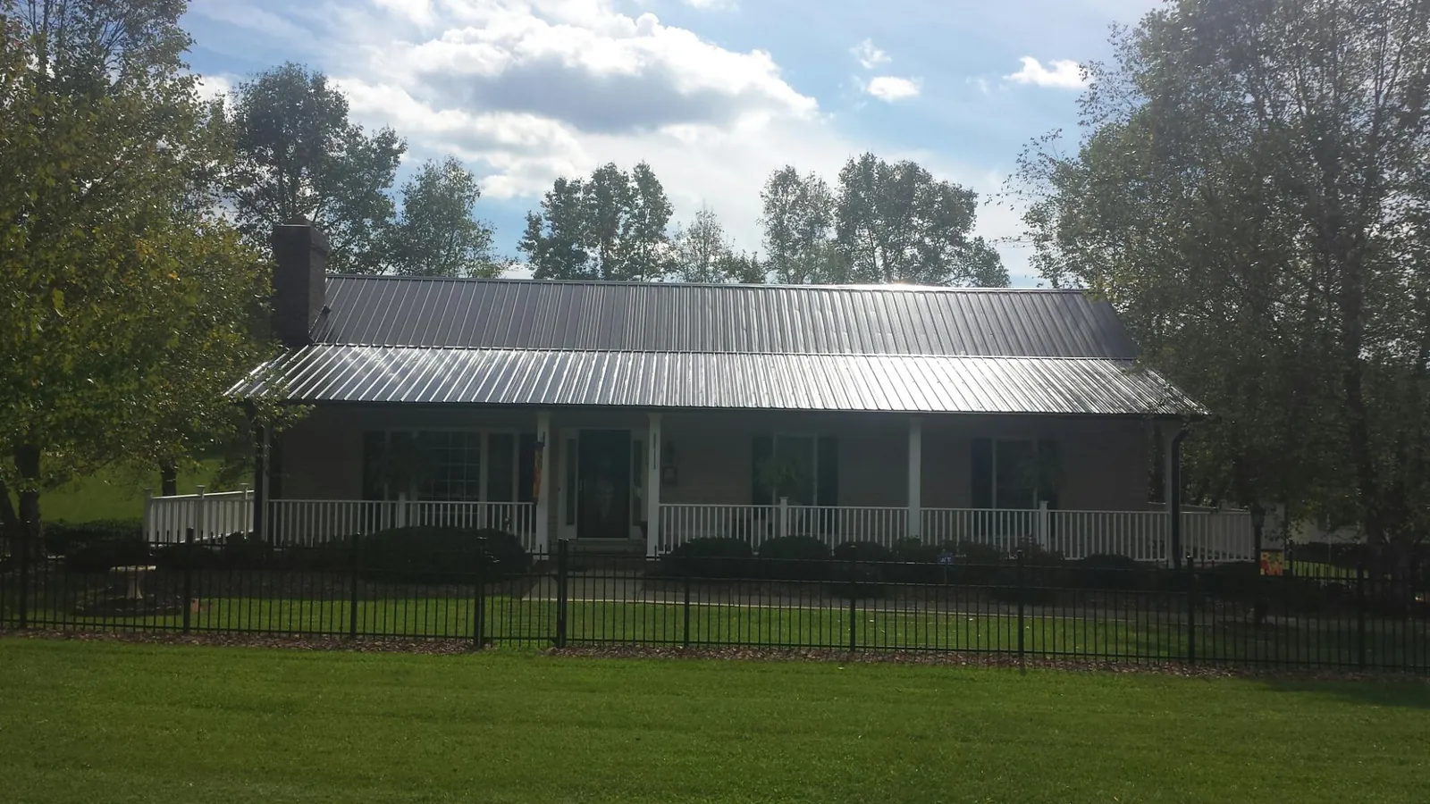 Gray metal roof on a brick ranch with a full width front porch — Gutter Guard Installation work by our crew in Sturgeon Bay