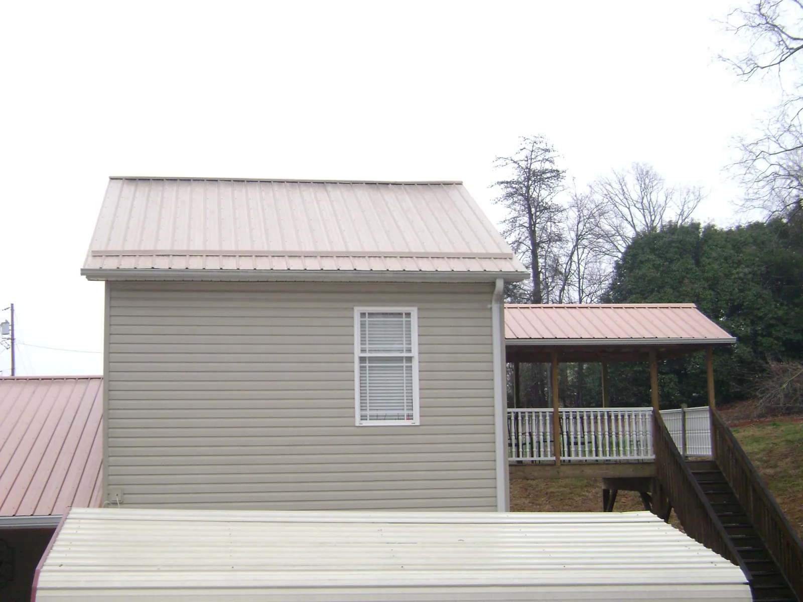 Tan metal roofs on a two story addition and attached porch, from a Roof Replacement job in Sturgeon Bay
